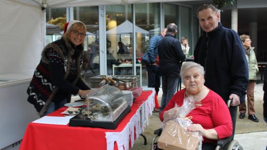 Twee bewoners van het WZC staan bij een standje op de kerstmarkt